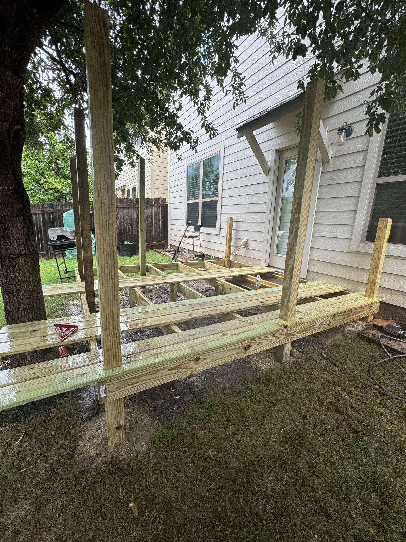 Fresh lumber posts and joists for a deck framed beside a house.
